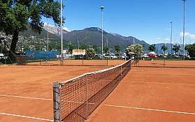 Campo da tennis all'aperto Campo da tennis in terra rossa con montagne sullo sfondo.