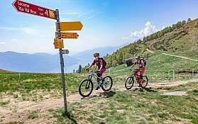 Ciclisti in montagna Due ciclisti su un sentiero di montagna con segnaletica.