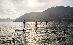 Paddleboarding al tramonto Gruppo di persone che praticano paddleboarding su un lago al tramonto.