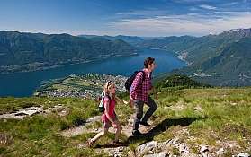 Paar wandert auf einem Berg mit Blick auf einen See und die Landschaft.