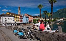 Coppia in riva al lago Una coppia si rilassa vicino al lago con biciclette a noleggio.