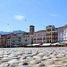 Vista della piazza con ciottoli e edifici storici colorati.