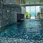 Piscina interna con pareti in pietra e vista panoramica.
