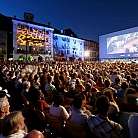 Una folla guarda un film proiettato all&#039;aperto di sera.