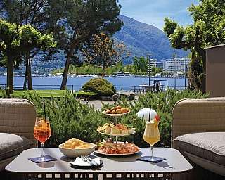 A table set with food and drinks overlooking a lake and mountains.