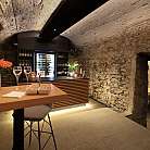 Bar con pareti in pietra e tavoli in legno, decorato con fiori.