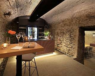 Salle avec des murs en pierre et des tables en bois, décorée avec des fleurs.