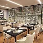 Ristorante moderno con tavoli, sedie e parete in pietra.