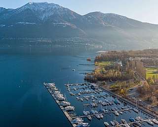 Port de plaisance avec yachts et montagnes en arrière-plan.