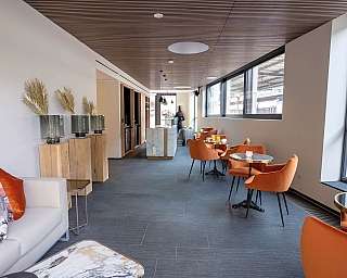 Spazio caffè elegante con sedie arancioni e decorazioni minimaliste.