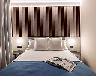 Letto con cuscini e libro su copriletto blu.