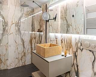 Salle de bain avec lavabo en bois et murs en marbre.