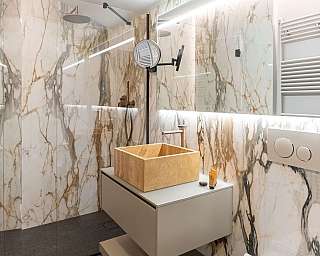 Salle de bain avec lavabo en bois et murs en marbre.