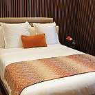 Letto elegante con biancheria bianca e decorazioni in legno.