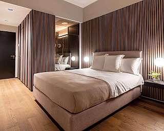Interno di una camera da letto con pareti in legno e illuminazione elegante.