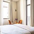 Interno di una camera con letto, tavolo e sedie.