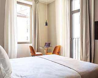 Chambre avec lit, table et chaises, lumière naturelle.