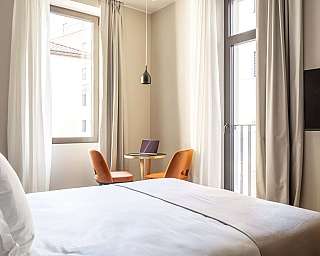 Chambre avec lit, table et chaises, lumière naturelle.