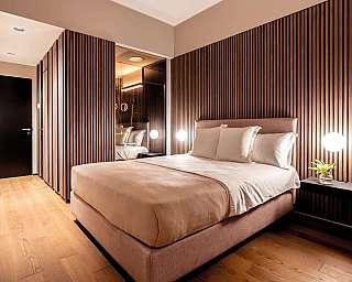 Interno di una camera da letto con pareti in legno e illuminazione elegante.