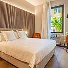 Interno di una camera con letto, sedie e finestra luminosa.