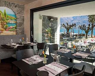 Modern dining area overlooking a scenic lake and outdoor seating.