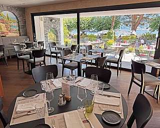 Innenansicht eines Restaurants mit Blick auf den See und Tische.