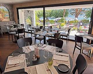 Modern dining area overlooking a scenic lake and outdoor seating.